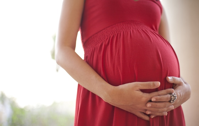 Woman holding her large pregnant stomach